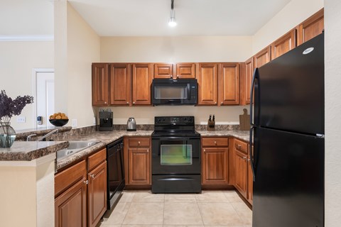 A kitchen with black appliances and wooden cabinets.